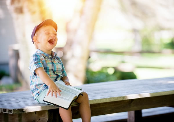 little kid reading book and laughing